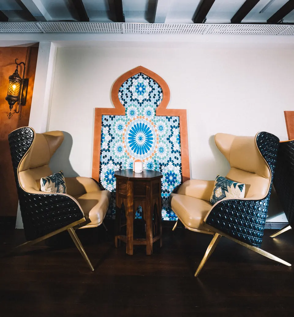 A lounge corner at Casa Marra: two wingback chairs beneath a zellige tile arch
